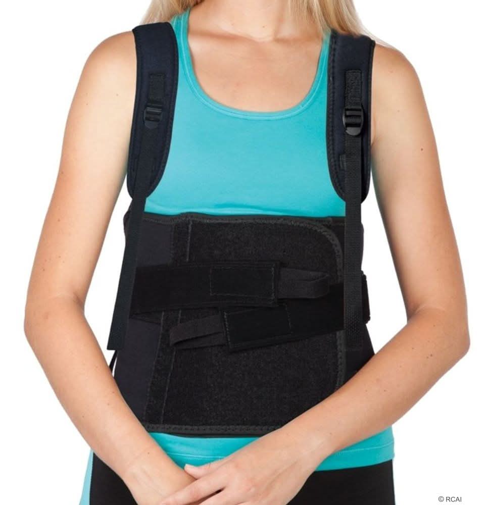 Black Thoracic Lumbar Support with adjustable side panels, worn over turquoise tank top, featuring padded shoulder straps,.